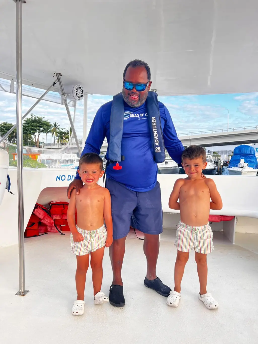 Seas N' Cays crew member in a branded blue shirt greeting guests on deck