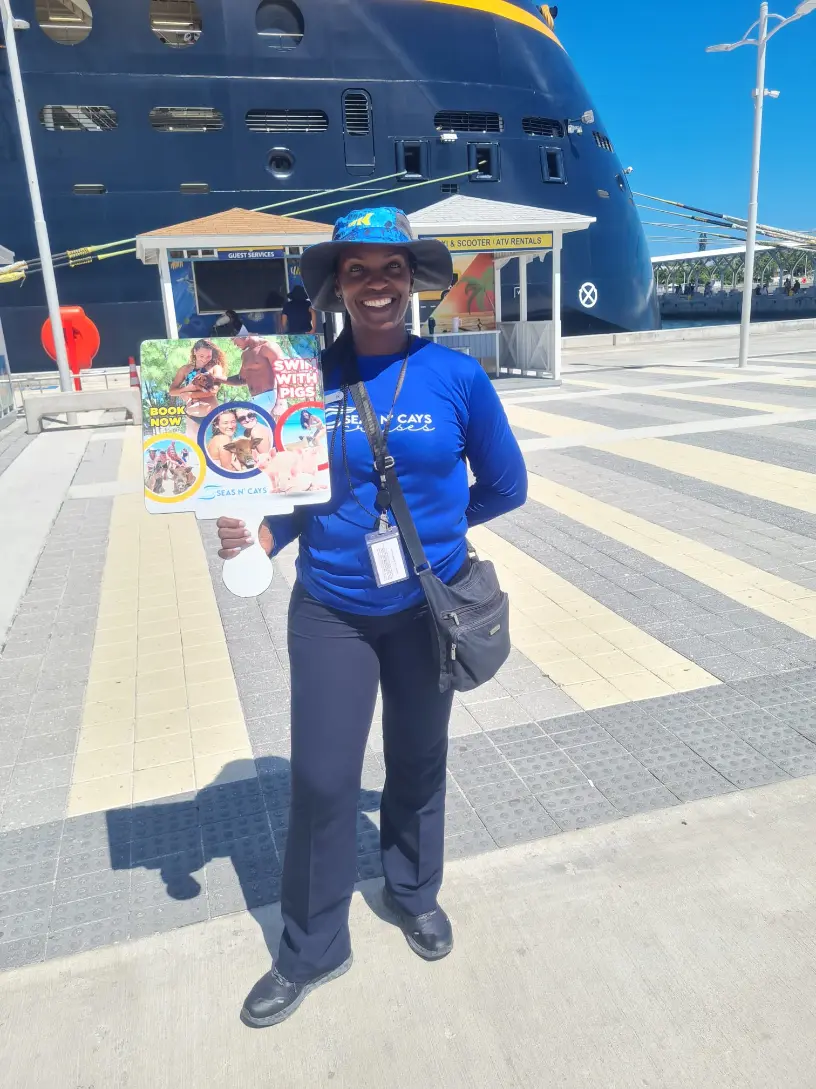 Seas N' Cays crew member in a branded blue shirt greeting cruise passengers at Prince George Wharf