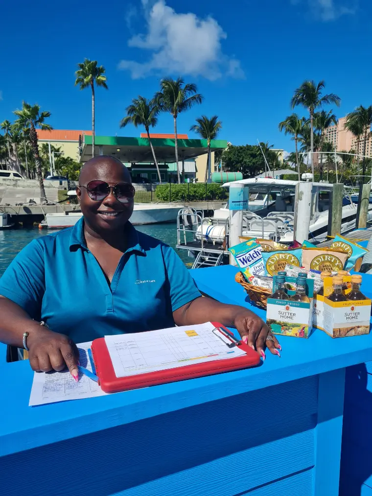 Seas N' Cays crew member at the cruise port booth with the tour sign-up table in Nassau