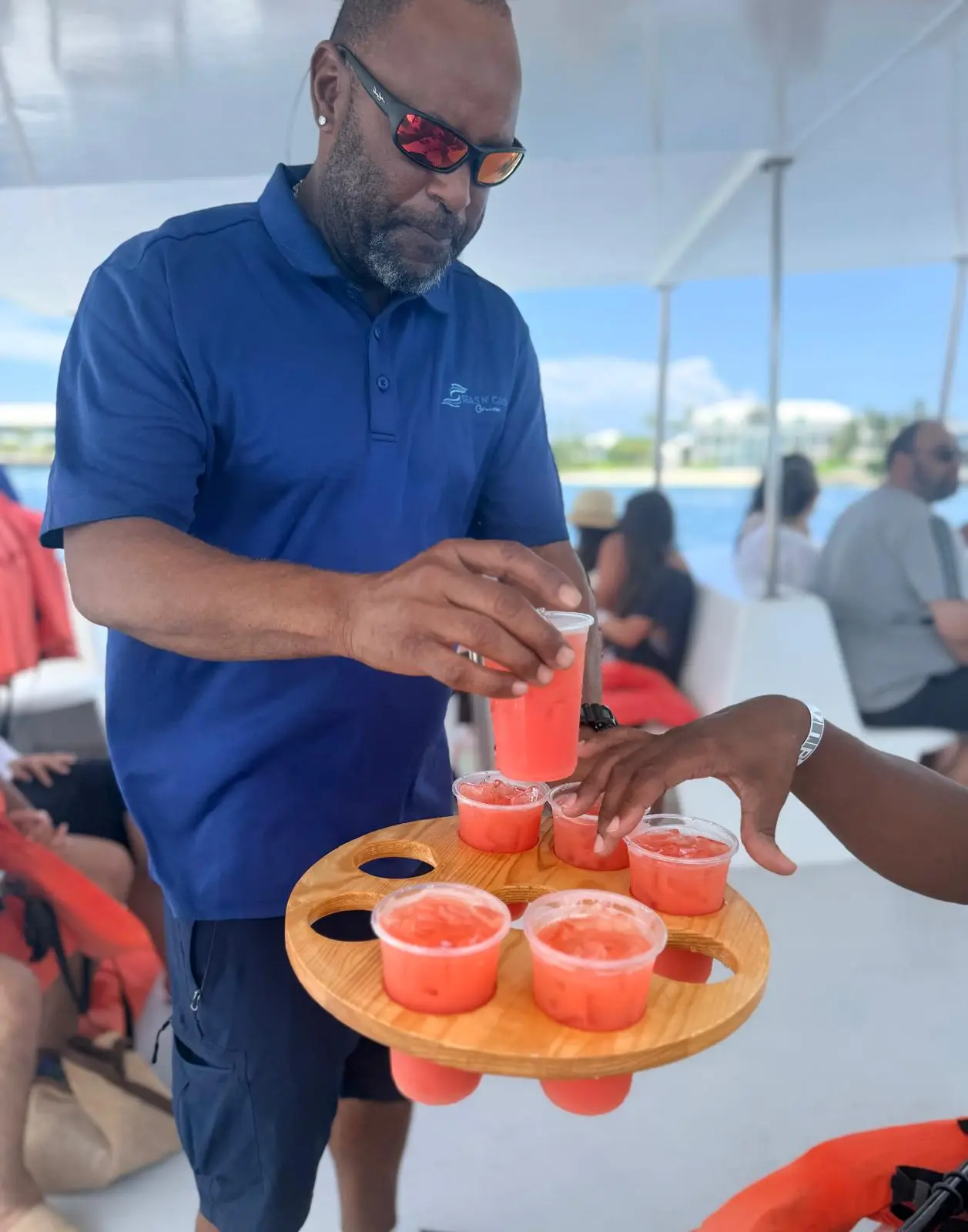 Seas N' Cays crew member serving rum punch to guests aboard the catamaran
