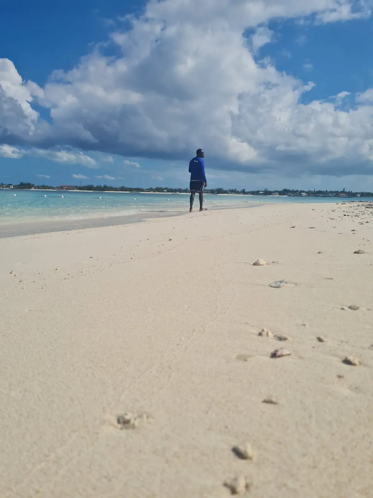 A single figure walking the quiet white-sand beach at Rose Island in the Bahamas