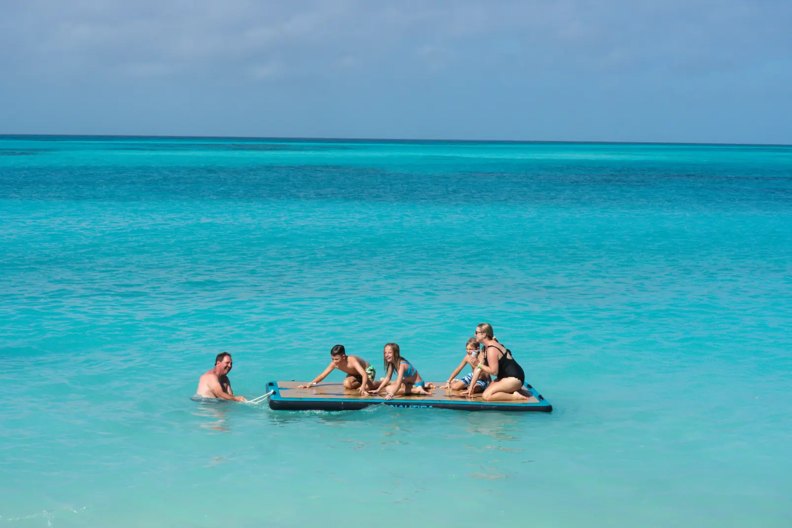 Guests swimming off the back of a Seas N' Cays catamaran in clear Bahamian water
